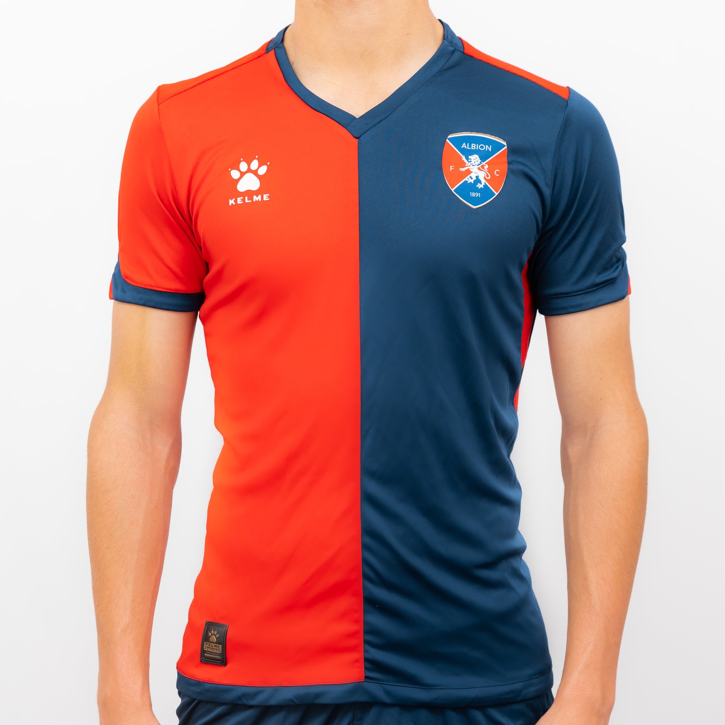 Camiseta Oficial de Albion Football Club. Imagen de frente torso. Camiseta mitad roja y mitad azul con el escudo del Leon en la parte derecha y el logo KELME en la parte izquierda. 